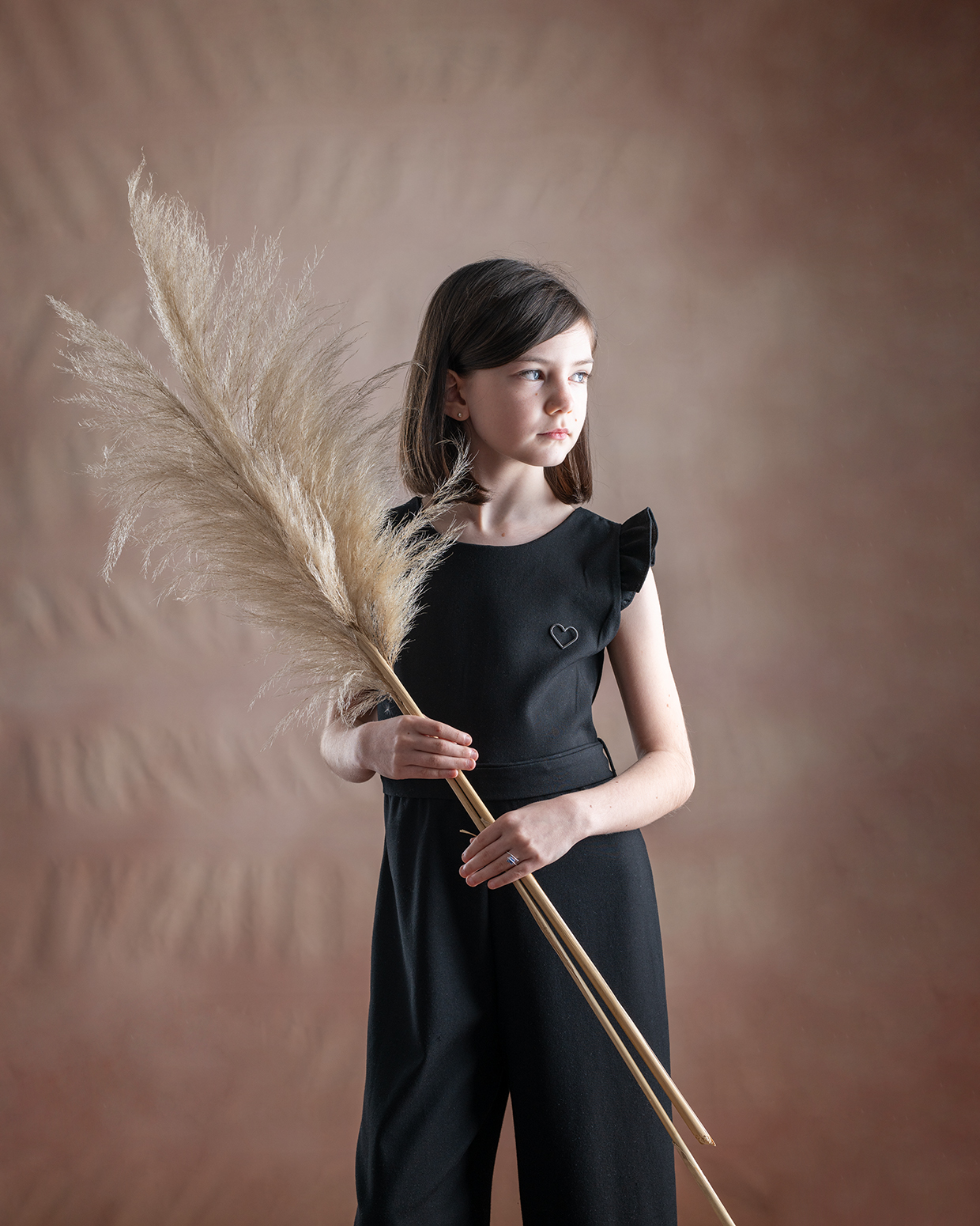 Fotografia Fine Art di bambina con vestito nero e fiori secchi in mano. Scatto realizzato in studio da Ferruccio Munzittu