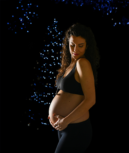 Foto di donna incinta con testa bassa e occhi chiusi, con bokeh natalizio, scattata da Ferruccio Munzittu